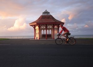 Cycling in Sussex: Photographer and cyclist Roff Smith riding past Edwardian kiosk on the seafront at Bexhill on the Sussex coast