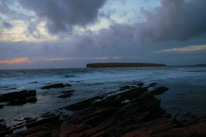 Lighthouse on the Brough of Birsay flickers to life on a wet and windy dusk off the north coast of Mainland, the largest of the Orkney Isles. The lighthouse was built in 1925 by David Stevenson, a relative of Robert Louis Stevenson