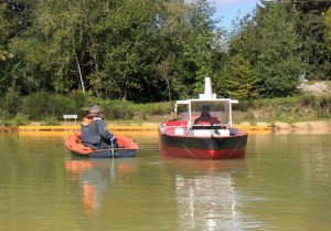 Instructors in dinghies on the lake at ship handling school at Port Revel following students who are piloting scale model freighters ad cargo ships and tankers