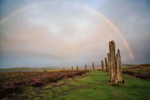 Rainbow arches over the ancient World Heritage listed Ring of Brodgar, a 5000 year old stone circle in Orkney, Scotland. Loch Harray in the background