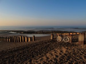 Classic touring bicycle on shingle beach, at sunrise, Bexhill-on-Sea, East Sussex, England