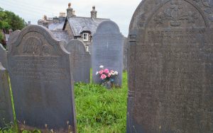 Plastic roses provide a rush of colour amongst the grey slate tomestones in old graveyard in Harlech