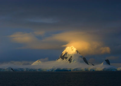 Dramatic light on ice-capped mountain peak in Antarctica
